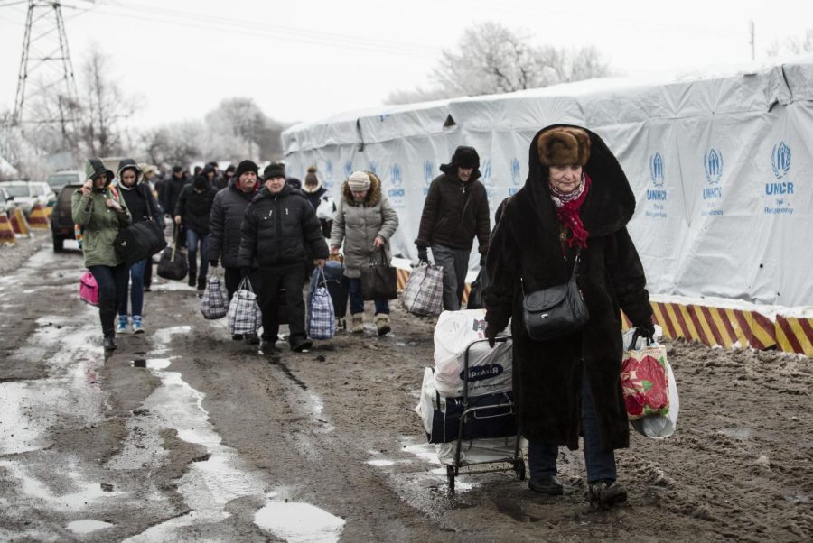 Ukrainian refugees rush towards a bus stop at a border crossing point in the Mayorsk, Donetsk region.  