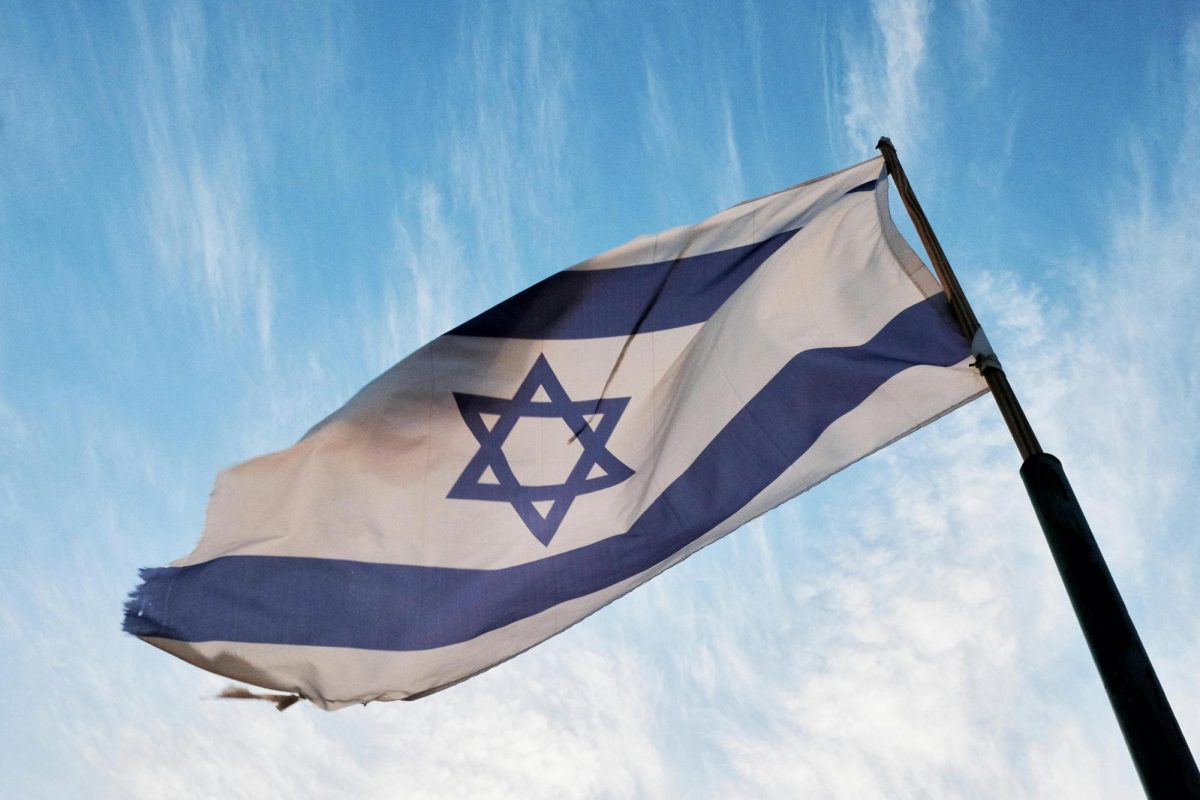 Israeli flag, torn up in the wind over a cloudy blue sky 